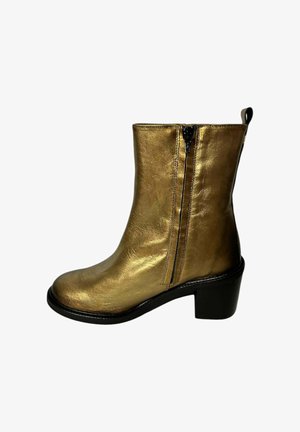 Botín de tobillo de cuero sintético dorado con tacón cuadrado, cremalleras laterales y textura suave. Presenta una puntera redondeada y una suela negra en contraste.