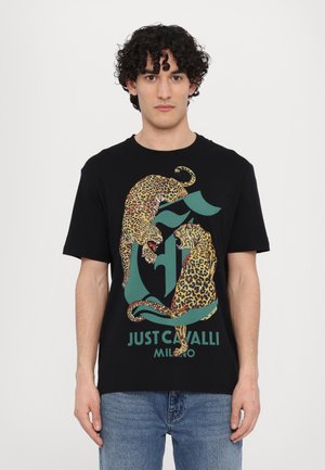 Black t-shirt featuring a graphic design of two leopards in yellow and brown spots, on a green logo background with "JUST CAVALLI MILANO" text.