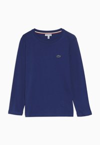 Granatowa, długi rękaw, bawełniana koszulka. Posiada okrągły dekolt i małe, zielone, haftowane logo na piersi. Gładka tekstura.