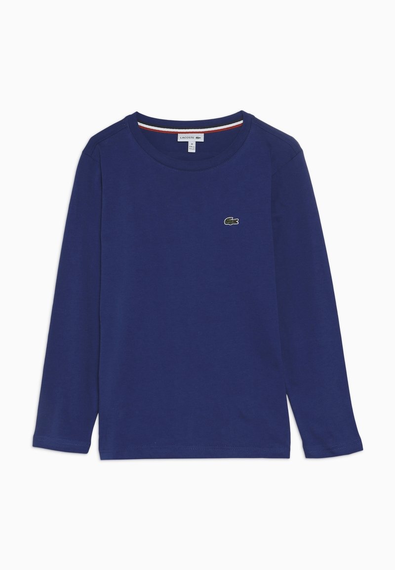 Granatowa, długi rękaw, bawełniana koszulka. Posiada okrągły dekolt i małe, zielone, haftowane logo na piersi. Gładka tekstura.