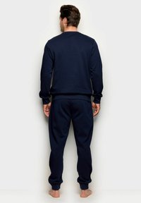 Completo composto da pullover e pantaloni jogger blu navy in tessuto morbido, con maniche lunghe, polsini a coste e vita elasticizzata. Design semplice.