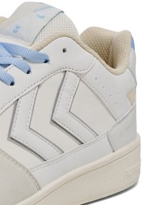 Białe skórzane trampki z niebieskimi sznurówkami, teksturowane wnętrze, szare akcenty w zygzak, oraz perforowane detale po bokach. Płaska gumowa podeszwa.