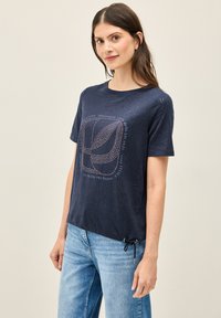 Marineblå t-shirt med korte ærmer og en afslappet pasform, med et struktureret bladmønster og silketryk i lysere nuancer.