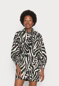 Vestido abotoado com padrão zebra, apresentando tons de verde, preto e creme. Tem um colarinho e mangas bufantes.