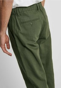 Relaxed-fit groene linnen broeken met een elastische tailleband, een enkele achterzak met knoopsluiting en gestikte details.
