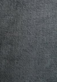 Gros plan d'un tissu en denim gris texturé avec un motif de tissage diagonal visible.