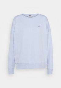 Sudadera azul claro con cuello redondo y hombros caídos. Presenta un pequeño logo en el pecho. Fabricada con un material de algodón suave.