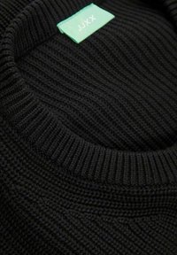Maglione nero lavorato a maglia con una texture a coste e un collo rotondo. Include un'etichetta verde con "JJXX" ricamata.