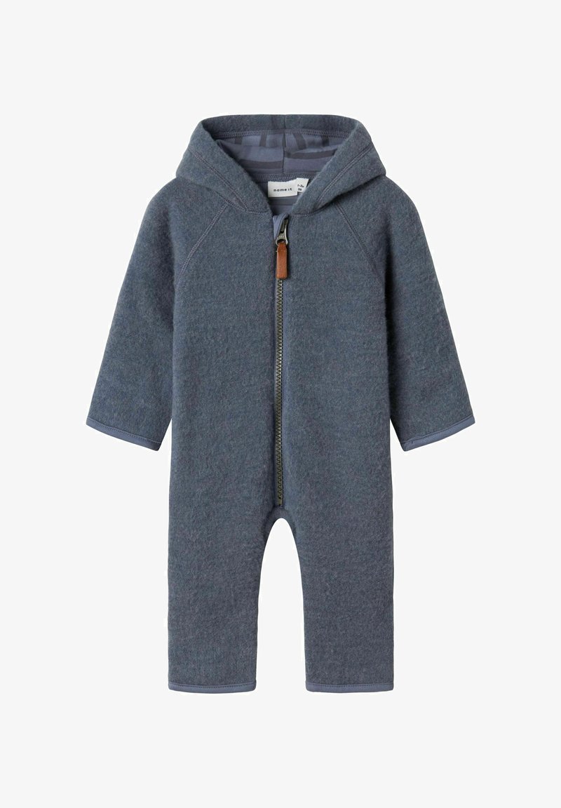 Grijze fleece éénstuk met capuchon, voorrits en leren trekknop in bruin. Voorzien van lange mouwen en benen tot aan de enkels.