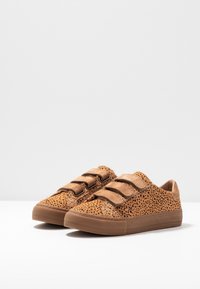 Sneakers marroni con texture a pois, dotati di tre fasce in velcro e suola in gomma. Design della punta arrotondata, stile minimale e casual.