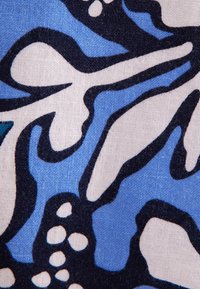 Baumwollstoff mit einem blauen Hintergrund, der große weiße und schwarze Blumenmuster sowie abstrakte Formen zeigt und ein strukturiertes Erscheinungsbild bietet.