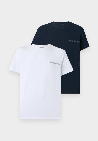 Dve kratkimi rokavi majici Emporio Armani z okroglim izrezom, ena v beli in ena v temno modri barvi, vsaka z majhnim logotipom blagovne znamke na levi strani prsi.