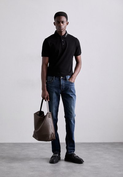 Svart polotröja med korta ärmar, blå denimjeans, svarta loafers och en brun läderhandväska. Enkel design och neutrala färger.