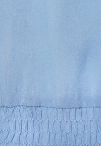 Tessuto blu chiaro con una trama testurizzata, dotato di un orlo elastico arriccicato nella parte inferiore, che indica elasticità e flessibilità.