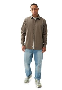 Brun button-up skjorte med krave, parret med lyseblå denim jeans og grå sneakers med et struktureret design.