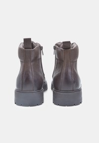 Stivali alla caviglia in pelle marrone con finitura texturizzata, cerniere laterali e suola robusta. Anello di trazione resistente sul retro per una facile calzata.