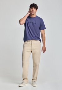 Lila bomulls t-shirt med "POLOCLUB" logotyp, ihopparad med beige rak ben byxor. Avslappnad design med vita sneakers. Enkelt mönster, avslappnad passform.