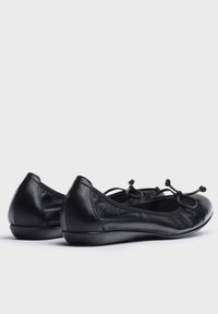 Bailarinas de cuero negro con punta redondeada y una textura suave. Presentan lazos decorativos en la parte delantera y un tacón bajo.