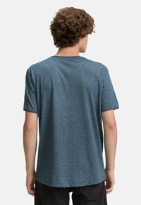 Kék gyapjú rövid ujjú póló kerek nyakkivágással és laza szabással, puha anyagból készült, finom textúrájú megjelenéssel.