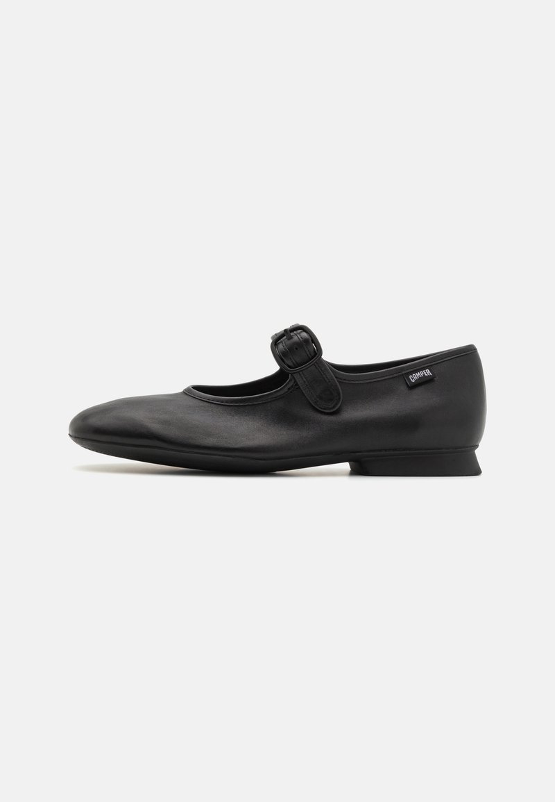 Chaussure plate Mary Jane en cuir noir avec bout arrondi, bride réglable à boucle et petit talon, vue de côté.