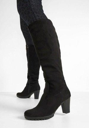 Bottes en suède noir au-dessus du genou avec un talon épais et une semelle texturée. Présente une finition lisse et un design effilé en haut.