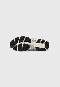 Running shoe sole, featuring a black rubber exterior with a textured grip pattern, white midsole, and green design accents.