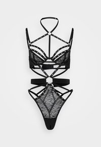Set di lingerie nera con design in mesh a motivo zebra, impreziosito da borchie argentate e dettagli intricati delle cinghie.