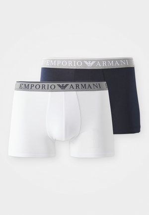 Deux paires de boxers pour hommes en blanc et bleu marine, avec une ceinture élastique grise portant le logo "Emporio Armani", texture de tissu lisse.