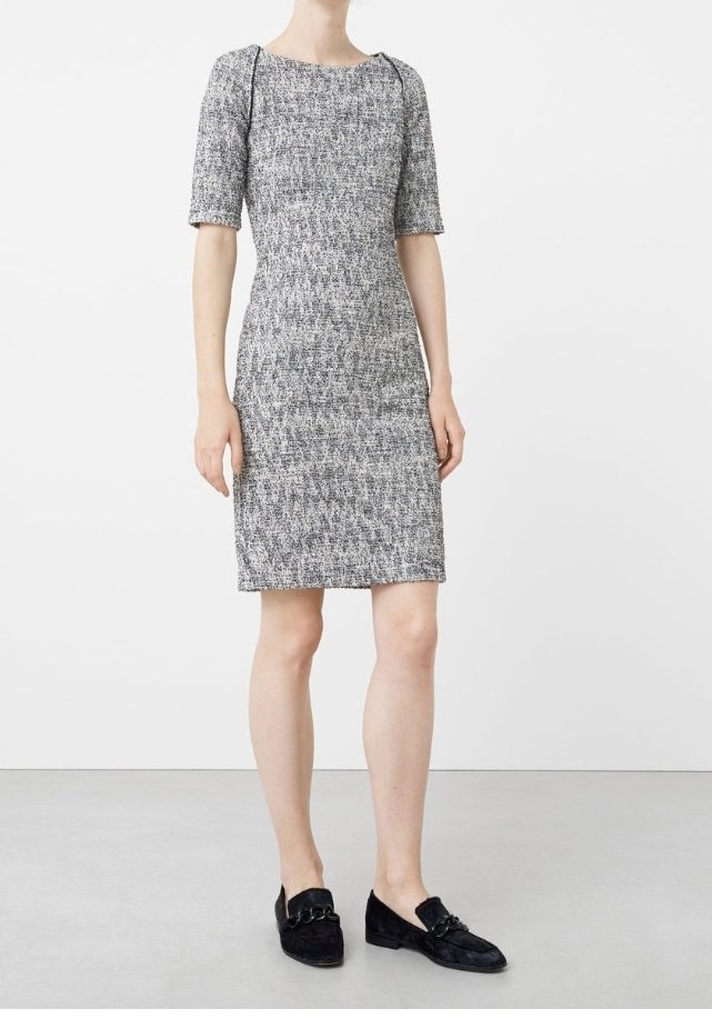 Harmaa ja valkoinen teksturoitu polvipituinen mekko, jossa on lyhyet hihat ja pyöreä pääntie, yhdistettynä mustiin loafer-kengiin, joissa on koristeellisia metalliosia.