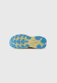 Semelle des chaussures Hoka avec un design texturé, dotée de crampons en caoutchouc bleu et d'une semelle intermédiaire beige, mettant en avant l'adhérence et la durabilité.