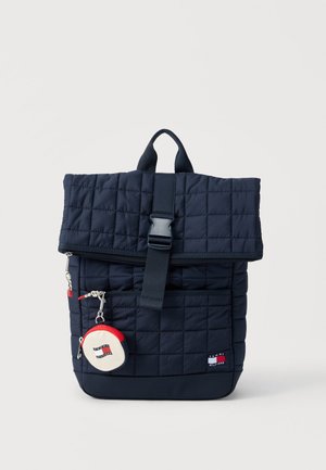 Marineblauer gesteppter Rucksack mit oberem Schnallenverschluss, Frontreißverschlusstasche und kleinem runden Täschchen mit einem roten, weißen und marineblauen Logodetail.