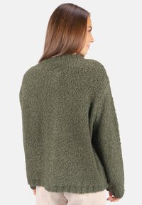 Olivgrüner, strukturiertes Sweatshirt aus kuscheligem Material. Besitzt einen lässigen Schnitt, überschnittene Schultern und einen abgerundeten Saum hinten.