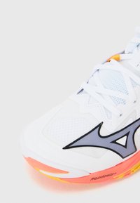 White athletic shoe with mesh details, black and gray accents, and a multicolored sole featuring orange and yellow highlights.