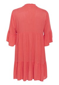 Vestido corto de color coral con mangas cortas, un ajuste relajado, escote con volantes y dobladillo en capas. Confeccionado en una tela ligera con una textura suave.