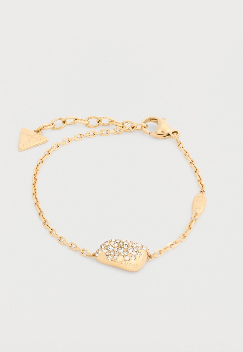 Βραχιόλι με χρυσή αλυσίδα και ορθογώνιο φυλαχτό διακοσμημένο με μικρούς διαφανείς κρυστάλλους και τριγωνικό φυλαχτό με λογότυπο κοντά στο κούμπωμα.