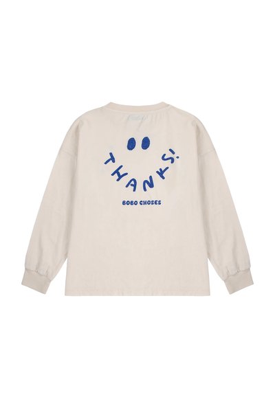 Krem majica dugih rukava od pamuka, s plavim natpisom "HVALA!" i s dvije točkaste oči, opuštenog kroja i rebrastim manžetama.