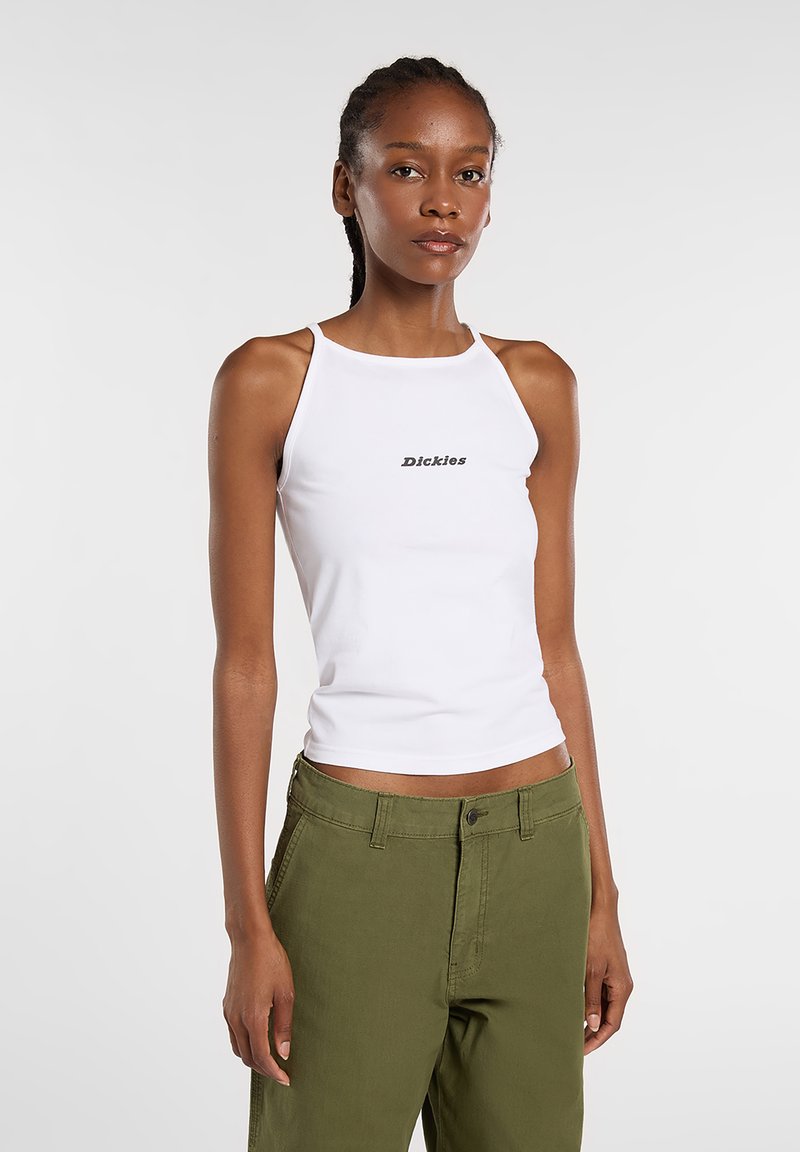 White tank top with a high neckline and thin straps featuring the word "Dickies" in black. Worn with olive green pants.