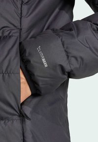Black insulated jacket with a smooth texture, features a zippered pocket, and "CLIMAWARM" branding on the cuff.