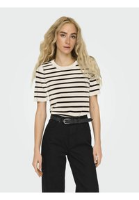 Stribet t-shirt med rund halsudskæring, der har sorte striber på en lys baggrund, parret med højtaljede sorte bukser og et sort bælte.