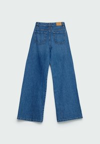 Jean bleu à jambes larges vu de dos avec deux poches arrière et un patch en cuir marron sur la ceinture.