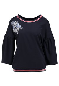 Top navy con scollatura rotonda, maniche a tre quarti a campana e design floreale ricamato in tonalità di blu. Presenta polsini a righe rosse e bianche.