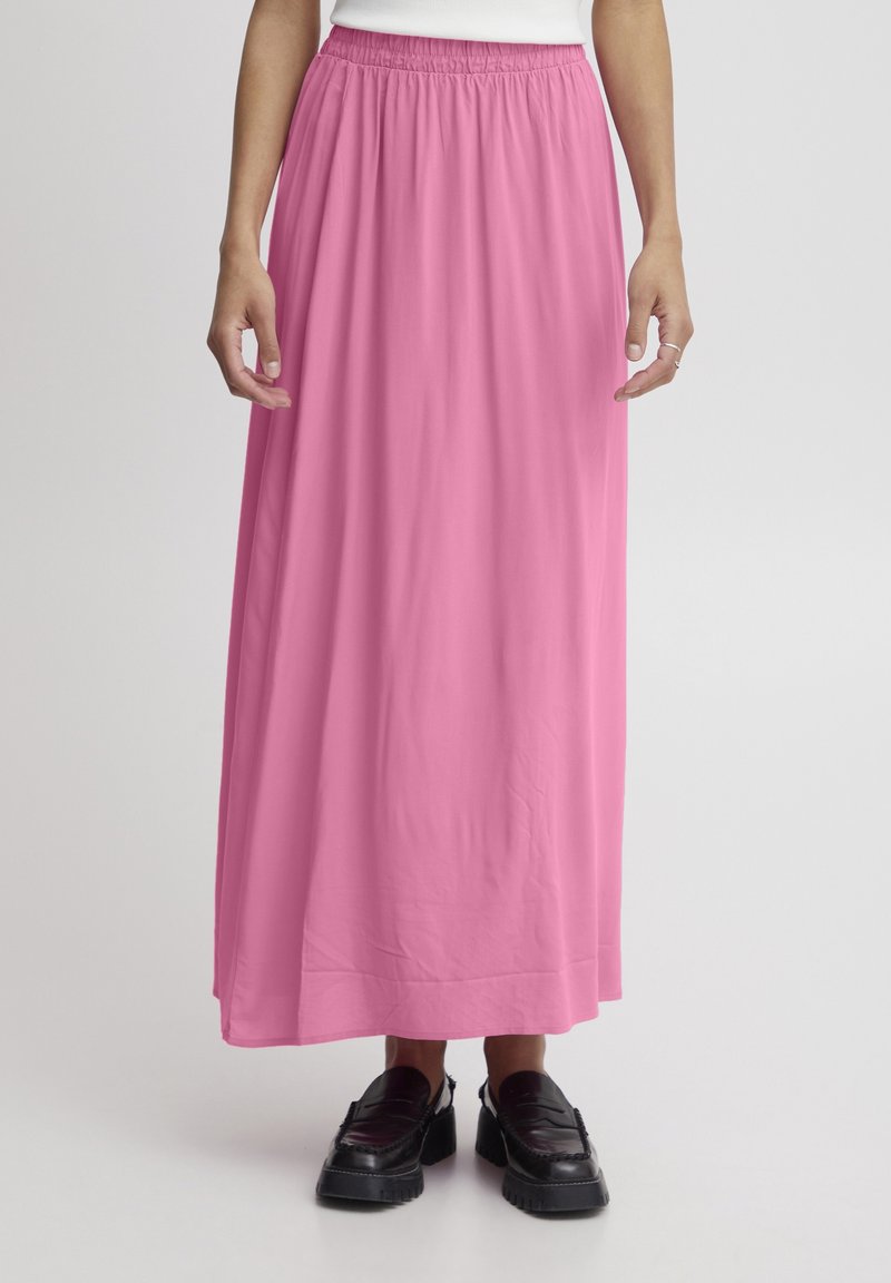 Larga falda rosa con una cintura elástica, que cae holgadamente para un ajuste relajado. Presenta una textura suave y se acompaña de zapatos de plataforma negros.