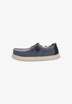 Zapato azul de tela tipo slip-on con superficie texturizada, plantilla de yute trenzado y forro interior con diseño. Cuenta con un lazo para facilitar el uso.