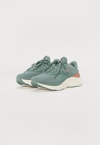 Scarpe da running verdi con una tomaia in maglia testurizzata, suola in gomma e intersuola ammortizzata con un accento pesca a contrasto sul tallone.