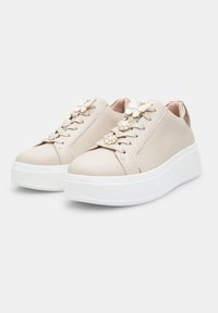 Sneakers beige con finitura in pelle liscia, fiori decorativi sui lacci e suola in piattaforma bianca. Presentano dettagli metallici sul tallone.