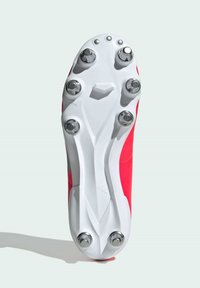 Scarpa da calcio rossa con suola bianca, dotata di sei tacchetti metallici e una finitura testurizzata. Progettata per garantire aderenza su superfici erbose.