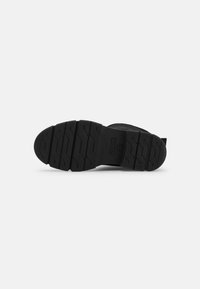 Suela de goma negra con una superficie texturizada y estampada. Presenta surcos y crestas para mayor tracción. Bordes limpios y lisos.