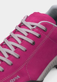 Baskets rose vif avec des lacets blancs et des coutures visibles, montrant la partie supérieure ainsi qu'une partie du col rembourré gris et de la semelle.