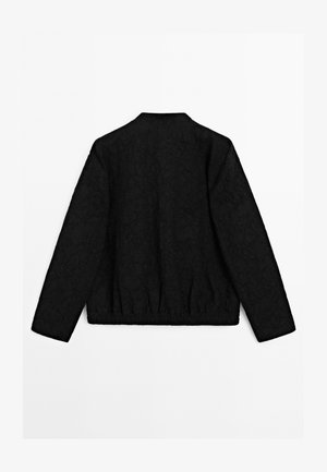 Veste noire à manches longues avec un motif floral subtil, ourlet élastique et sans fermetures visibles, vue de dos sur fond blanc.