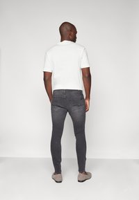 Witte T-shirt met korte mouwen, grijze slim-fit jeans en grijze schoenen. Gladde stof, aansluitend ontwerp, eenkleurig en minimalistische stijl.